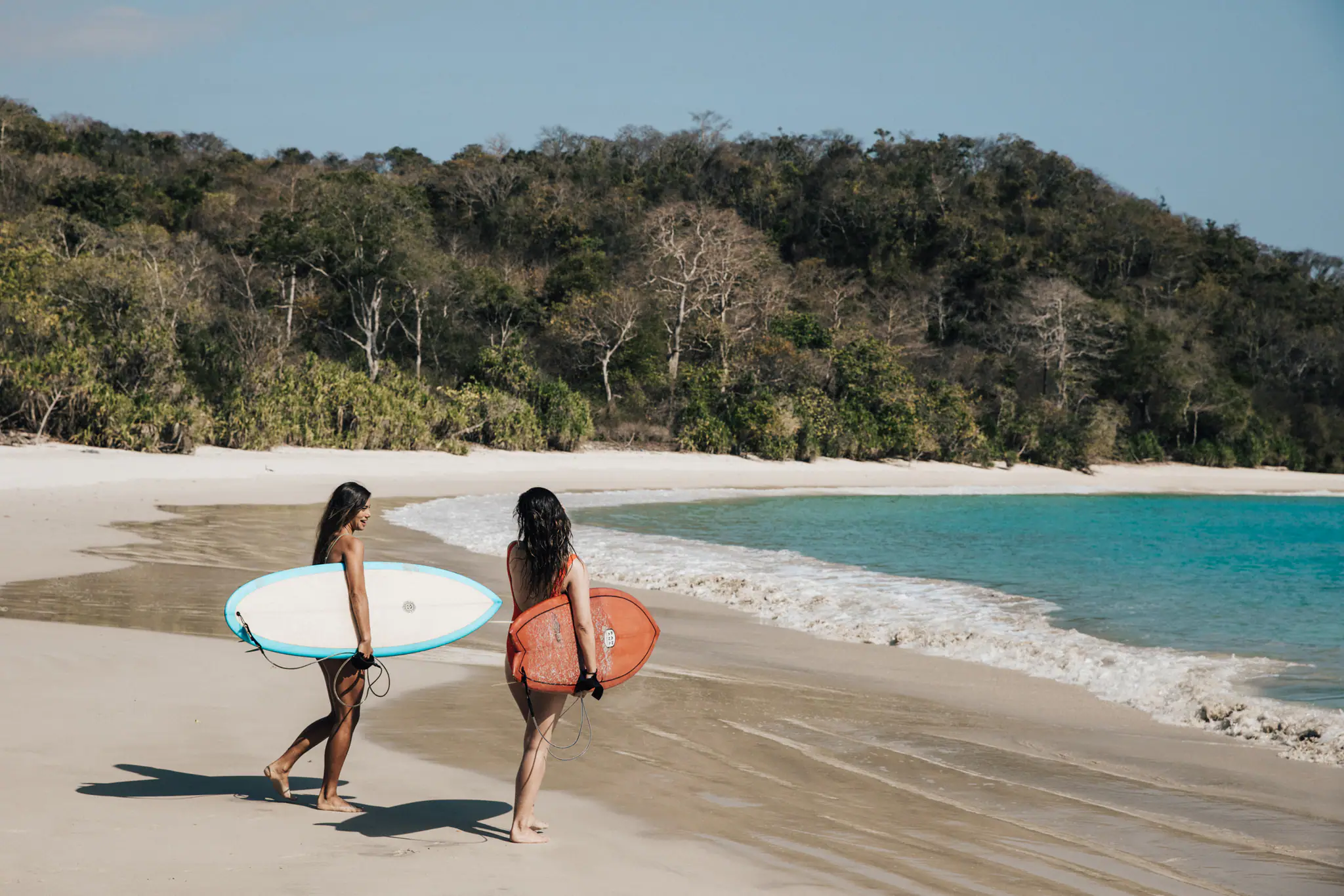 Kudanil Explorer Expedition Yacht | Guests carrying surfboards on beach