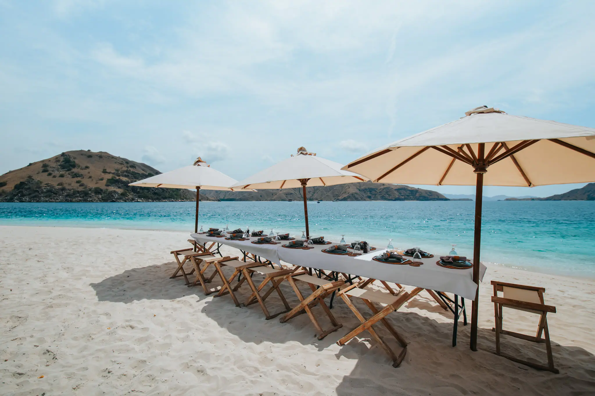 The Maj Oceanic Contemporary Phinisi Yacht | Beach dining setup with parasols